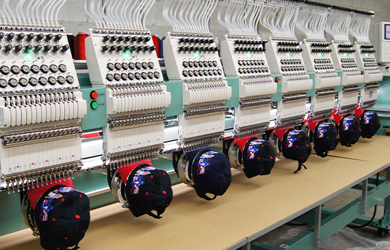 A shop of reliable embroidery equipment recently financed by Beacon Funding work to stitch black hats together.