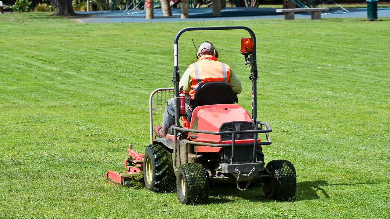 man-driving-a-mower-across-a-lawn