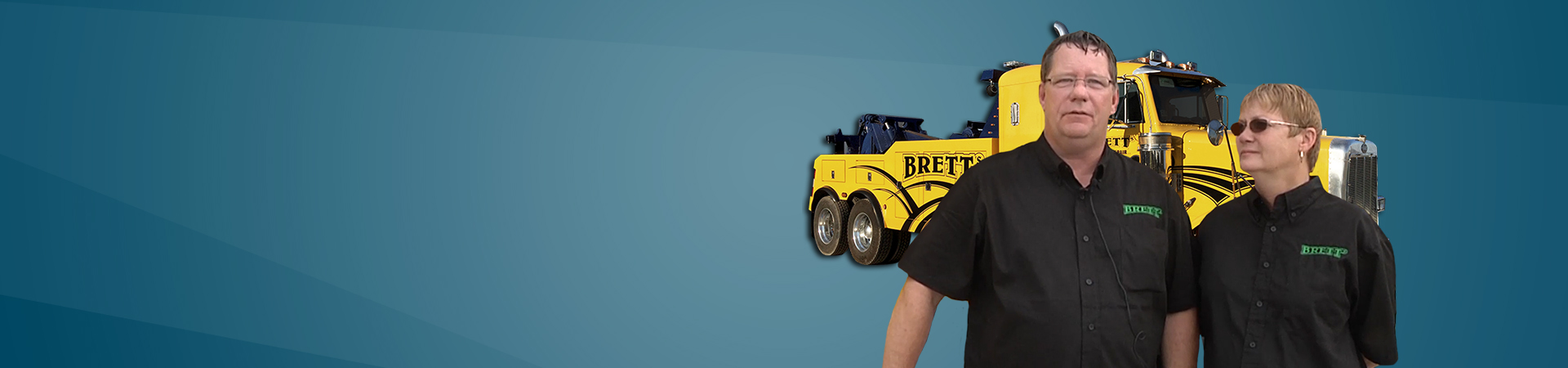 Brett’s Towing with man and woman owners with yellow heavy duty tow truck behind them