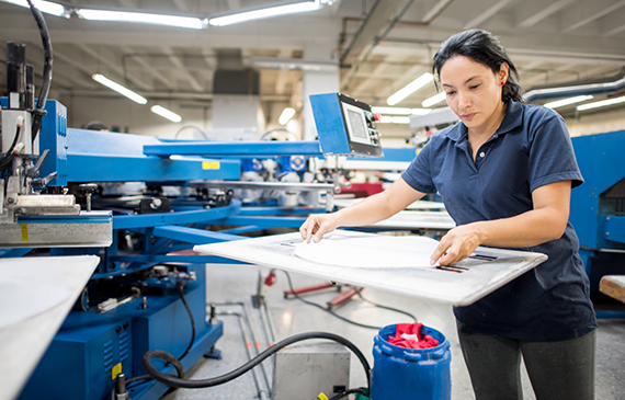 A printing press operator places fabric on an automatic printing press.