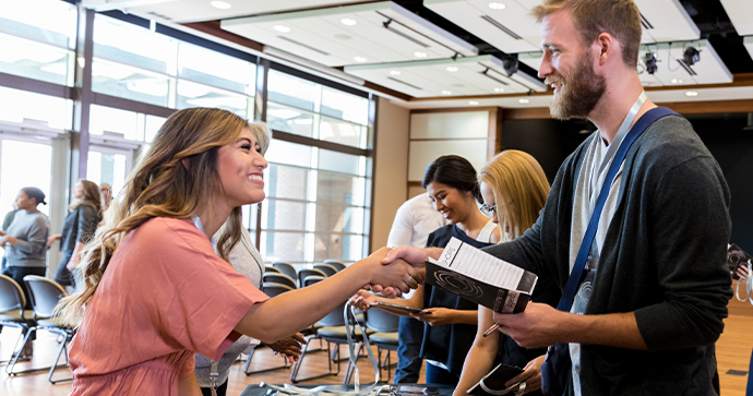 A smiling business owner shakes hands with a friendly Beacon Funding financing consultant.