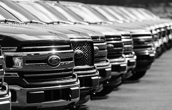 A fleet of new trucks line up the parking lot of a towing business.