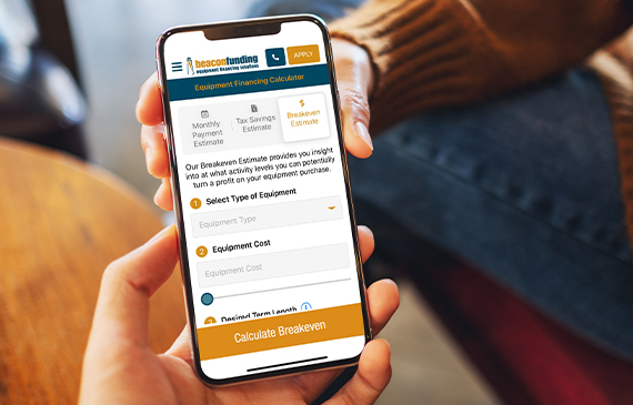A business owner uses Beacon Funding's breakeven estimate app on their mobile phone. A business owner uses Beacon Funding's breakeven estimate app on their mobile phone.