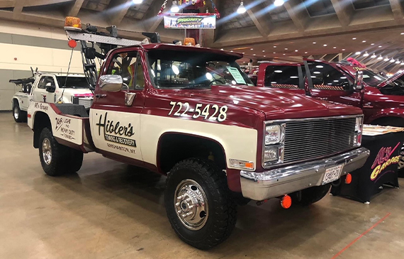 A shiny medium tow truck stands out from a fleet of trucks in the middle of a tow show. A shiny medium tow truck stands out from a fleet of trucks in the middle of a tow show.