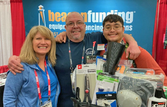 Photo of smiling David Gambardella and his son Pasquale in front Beacon Funding's tradeshow booth. Photo of smiling David Gambardella and his son Pasquale in front Beacon Funding's tradeshow booth.