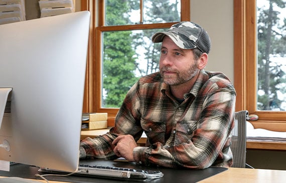 A worried landscaping business owner checks his business bank account on his desktop. 