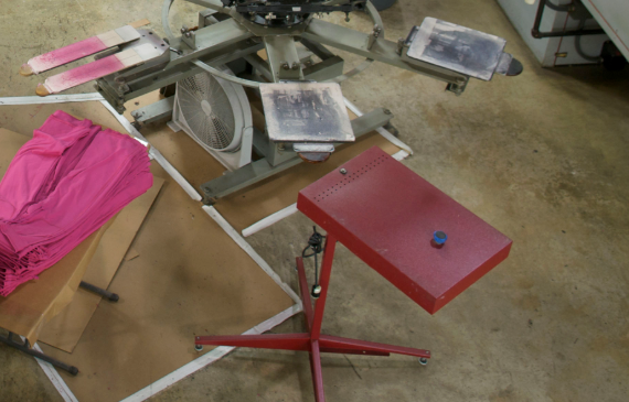 A small, red flash unit sits on a cement production floor with a cooling fan sitting next to it. A small, red flash unit sits on a cement production floor with a cooling fan sitting next to it.