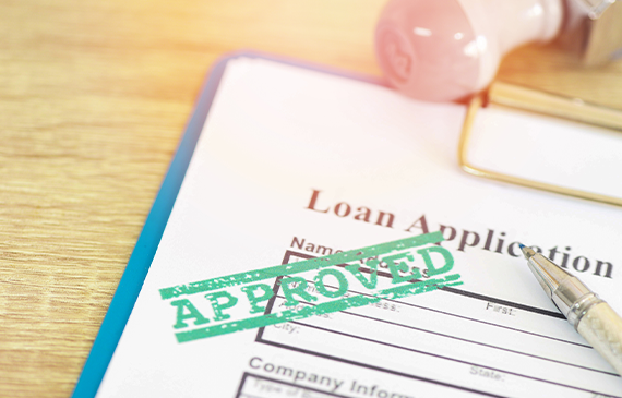 Loan application stamped ‘Approved’ on a clipboard, symbolizing how equipment financing through Beacon Funding can make it easier for businesses to secure capital and quickly get the equipment they need to grow.
