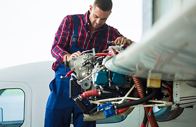 An aviation mechanic inspects and checks an opened airplane engine.