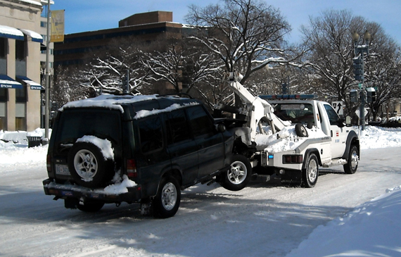 Two truck towes a vehicle in the snow.