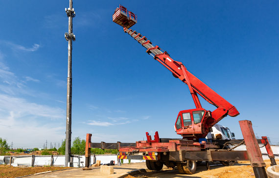 An operator raises the boom on a bright red truck to work on repairing a sign post. An operator raises the boom on a bright red truck to work on repairing a sign post.