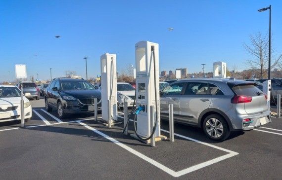 A group of electric vehicles are connected to charging stations in a public parking lot.