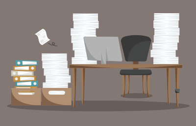 A tidy desk with a computer is next to a stack of pile of papers and books.