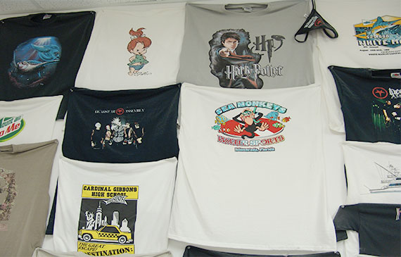 A collection of t-shirt with different designs lays on a table. A collection of t-shirt with different designs lays on a table.