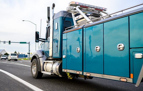A blue heavy-wrecker drives down the highway after getting financed by Beacon Funding.