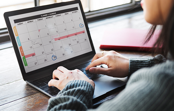 A businesswoman looks at her planner on her laptop. A businesswoman looks at her planner on her laptop.
