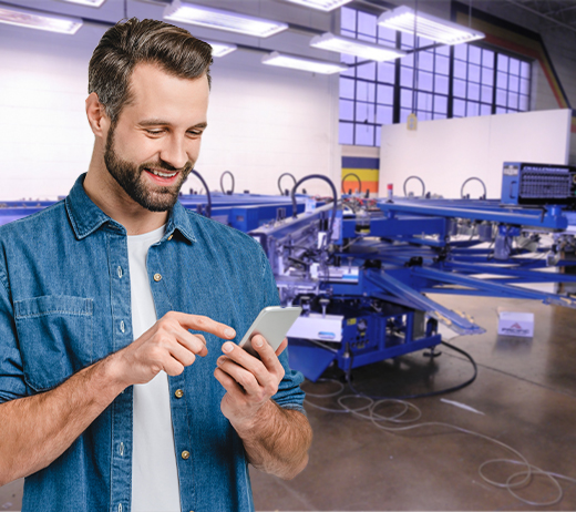 Man looking at phone, screen printing equipment
