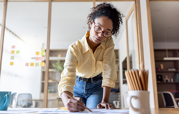 Planning equipment financing: woman reviewing paperwork at a desk, Beacon Funding lease-to-own guide