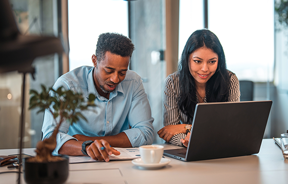Two people reviewing financing paperwork and a laptop together, Beacon Funding lease-to-own guide
