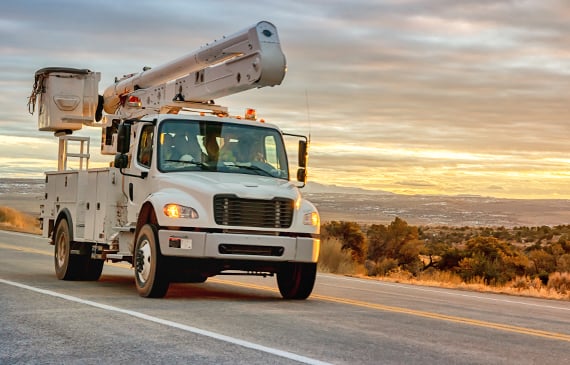 Boom truck drives down a highway with a mountainous landscape in the background. Boom truck drives down a highway with a mountainous landscape in the background.