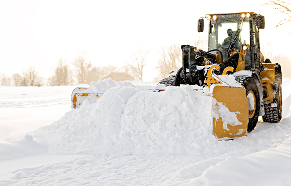 A pay loader operator plows snow.