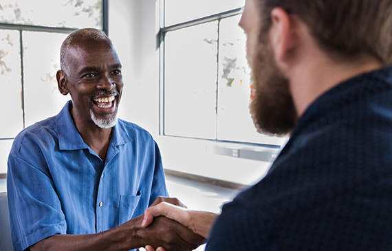 Two smiling business owners shake hands after financing equipment together. Two smiling business owners shake hands after financing equipment together.